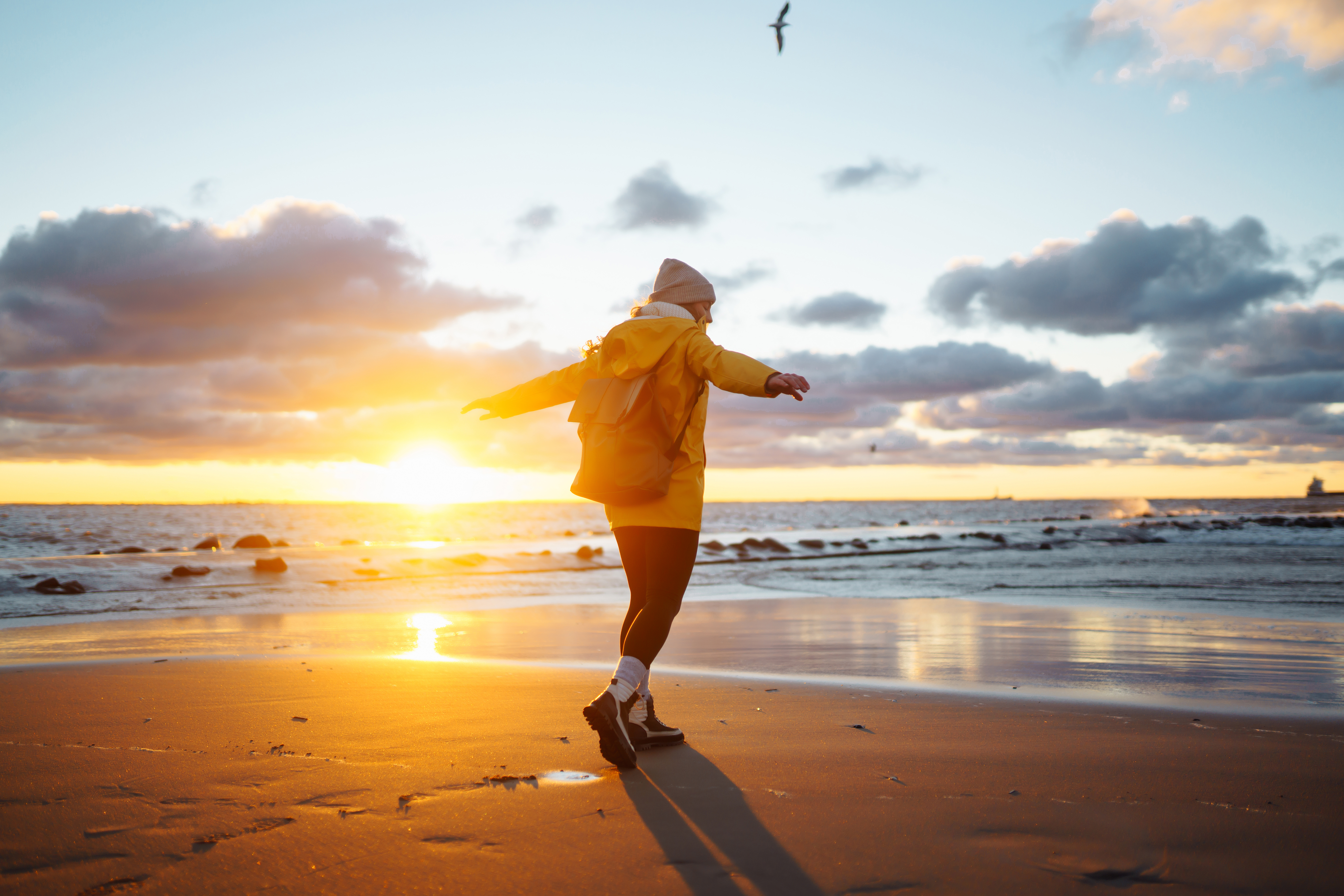 Tourist in yellow jacket enjoying sea landscape at sunset. Lifestyle, travel, nature, active life.